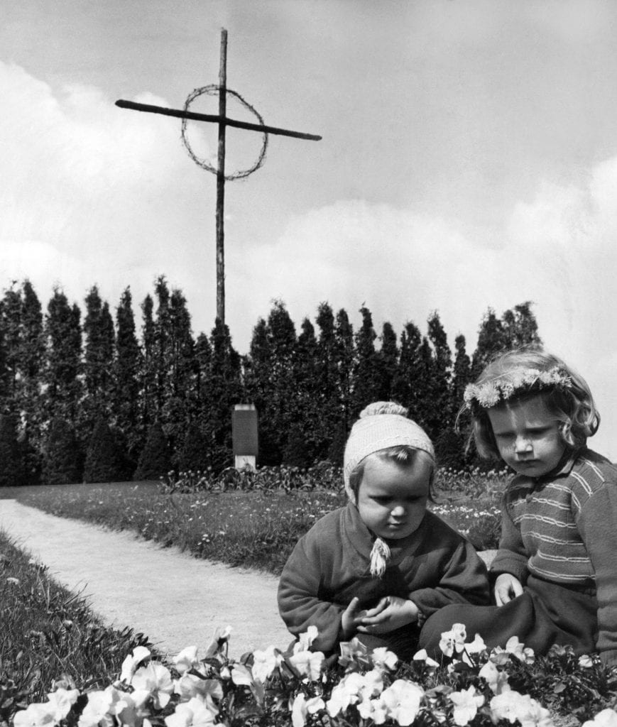 Children at the cemetery of Lidice, Czechoslovakia, on May 20, 1957, where the victims of the 1942 destruction of the village by Nazi troops are buried. The tall cross in the background is said to have been made from the charred beams of Lidice farm houses. (AP Photo/Czech News Agency)